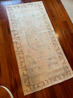 Measures 3'4.5" x 7  The palette is soft and muted to include salmon, blue, golden yellow and a burnt umber.  This is a vintage Turkish rug approximately 60 years old. Handmade with wool.  