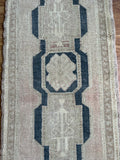 Dimensions: 1'7.5" x 3'1"  Palette includes red/pink undertones, navy, taupe and wheat.  Handmade c.1960 wool rug, imported by me from Turkey.