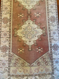 Dimensions: 2'6.5" x 9'1"  Palette includes a muted pink with more brown and red undertones versus true pink, blue, green, ecru, light yellow, and brown in the thin lines around the patterns.  This is a vintage Turkish runner from the 1940's made of 100% soft organic wool. It has been professionally cleaned. 